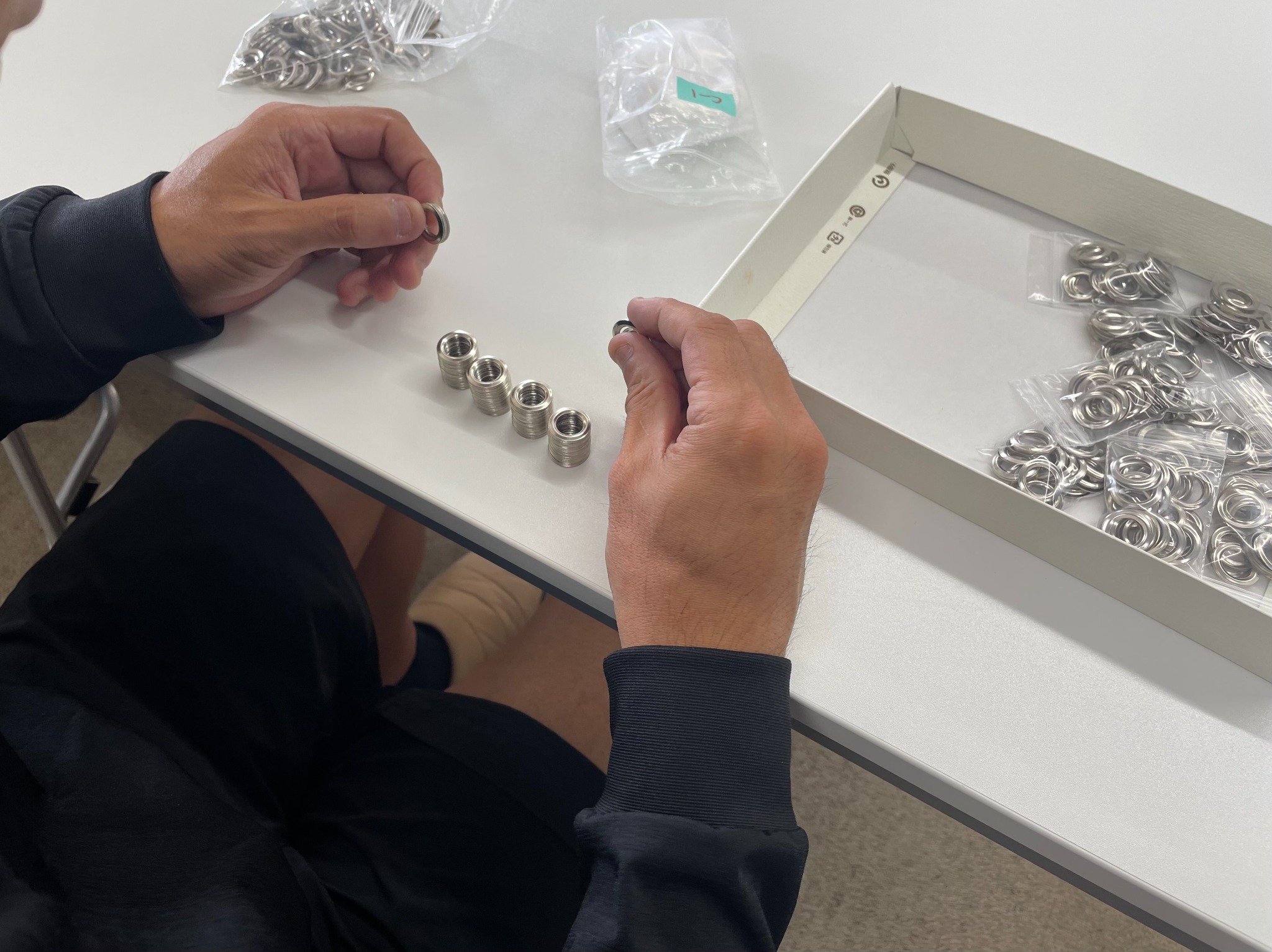 小さな金属部品を丁寧に扱い、室内で軽作業に取り組む様子